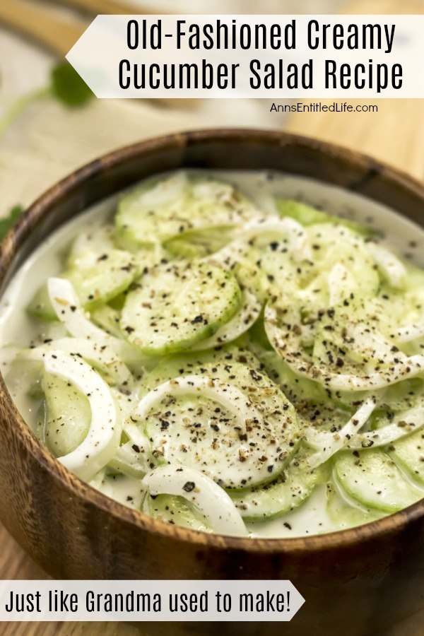 An overhead, close-up view of a wooden bowl filled with creamy cucumber salad.
